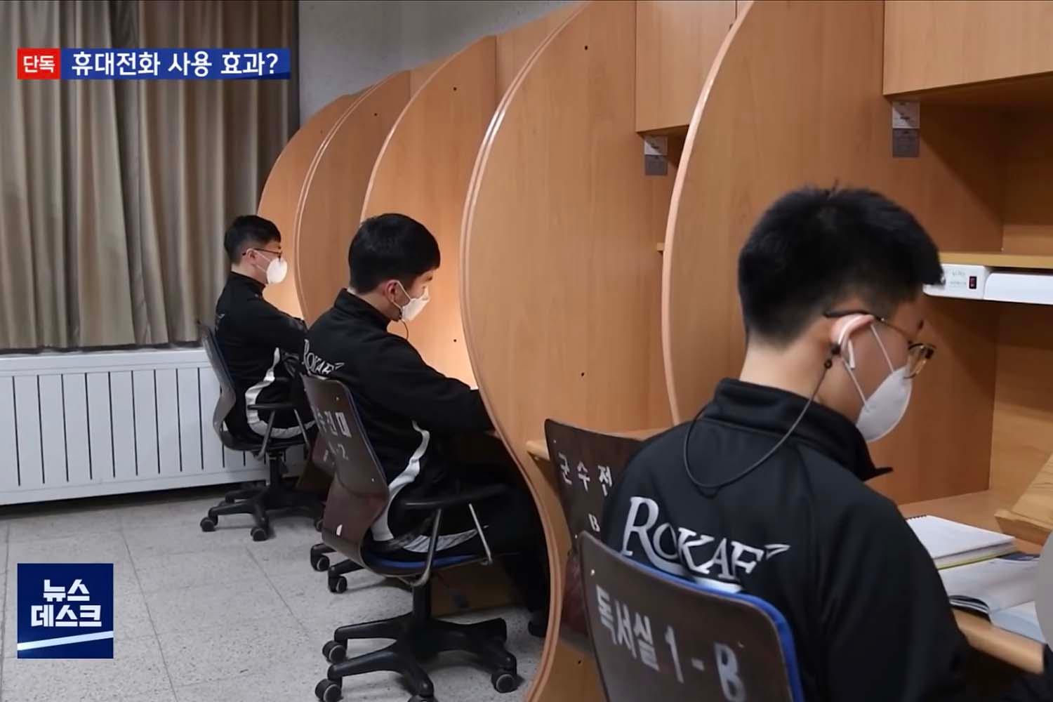 ทหารเกาหลีใต้ในเครื่องแบบนั่งอยู่ที่ห้องอ่านหนังสือขณะใช้โทรศัพท์มือถือในกองทัพ