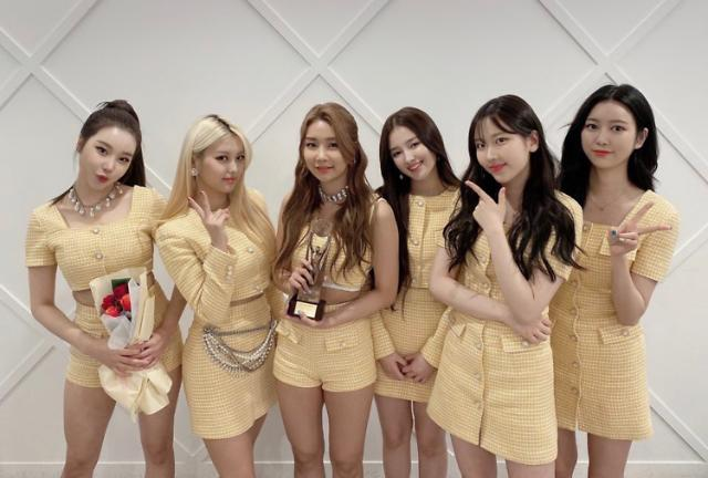 MOMOLAND 團體合照，成員們站在一起，背景為白色，穿著精緻的服飾