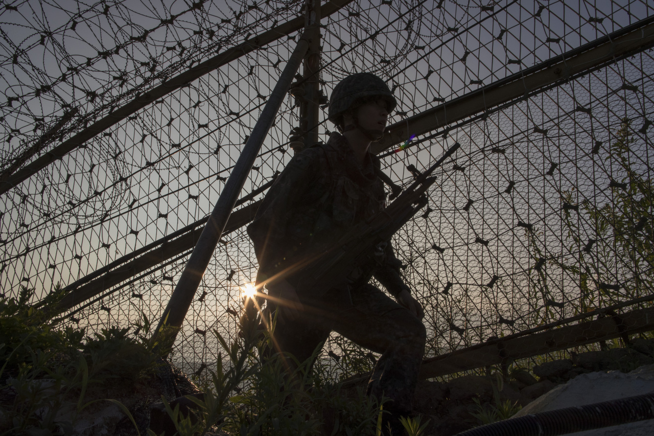 軍人在非軍事區的鐵絲網前站立，反映出南北韓之間緊張的邊界情勢與軍事戒備。