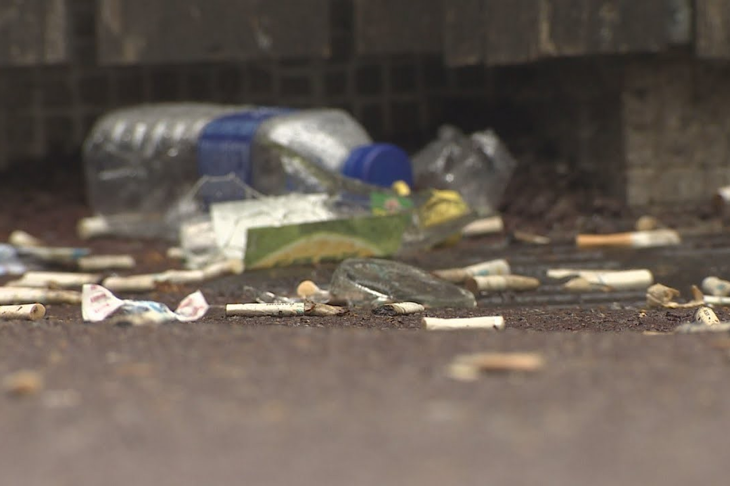 地面上的菸蒂和垃圾,反映了韓國江北區的環境問題和政府的回收措施。