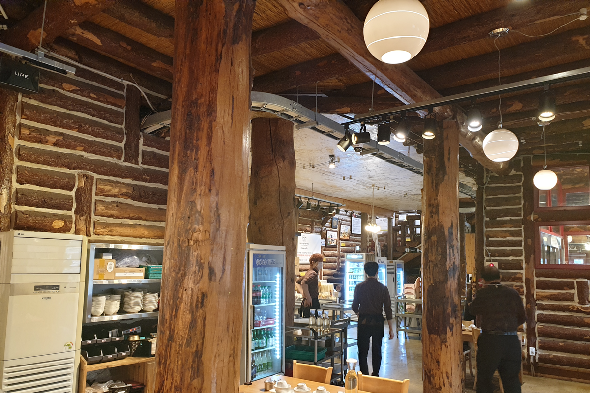 다람쥐마을 누룽지백숙의 내부, 벨 스타일 조명과 나무 기둥이 눈에 띄는 장면입니다.