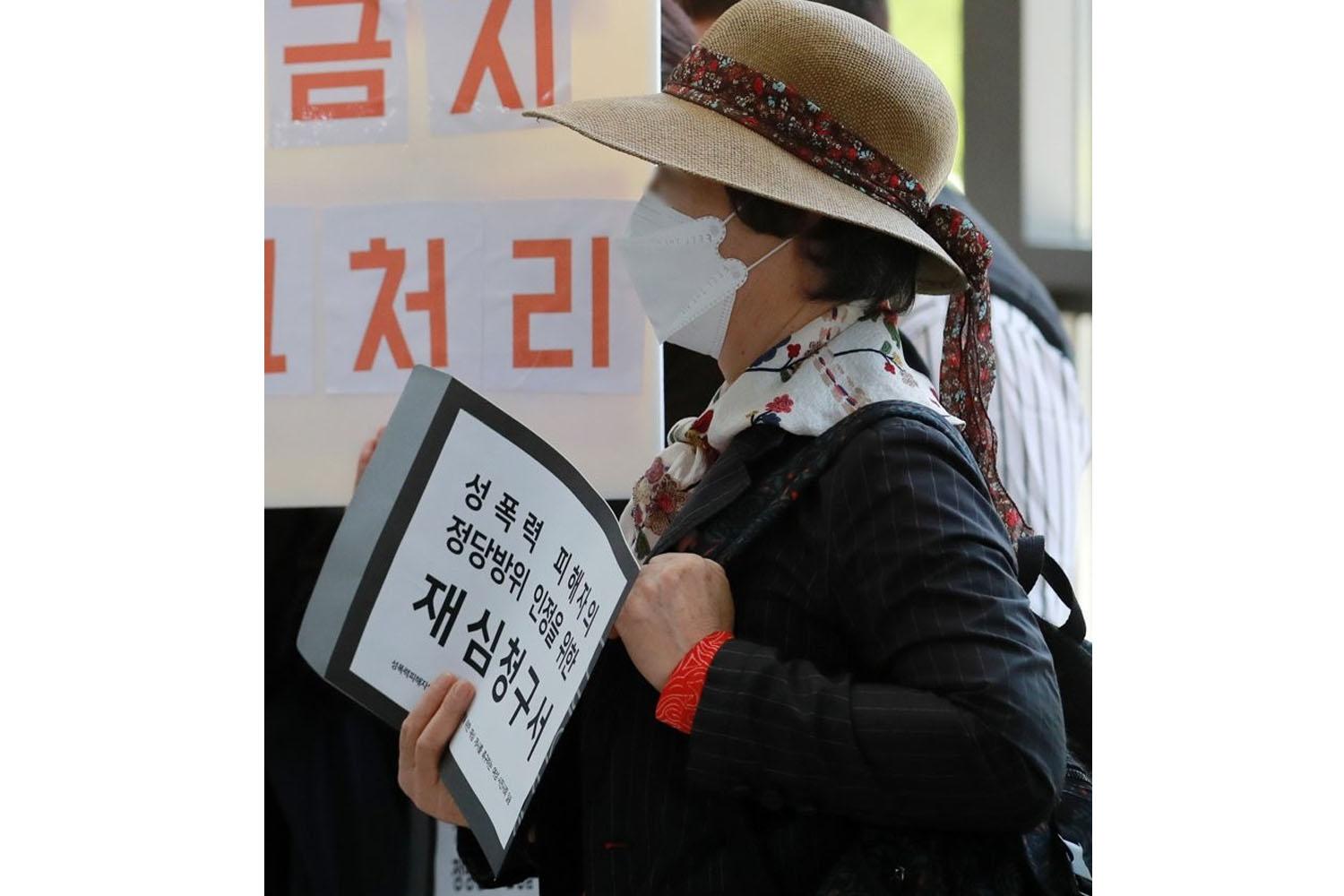 ผู้หญิงถือเอกสารคำร้องสำหรับพิจารณาคดีการข่มขืน ณ ศาลปูซาน ประเทศเกาหลีใต้
