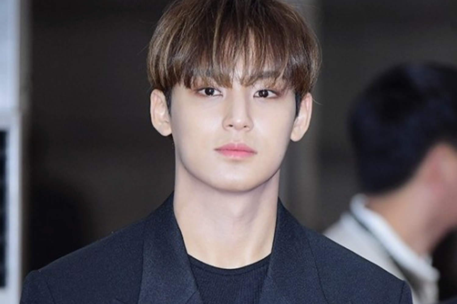 穿著黑色西裝外套的人出現在公共場合，可能是在首爾舉行的某個紅毯或媒體見面會中。