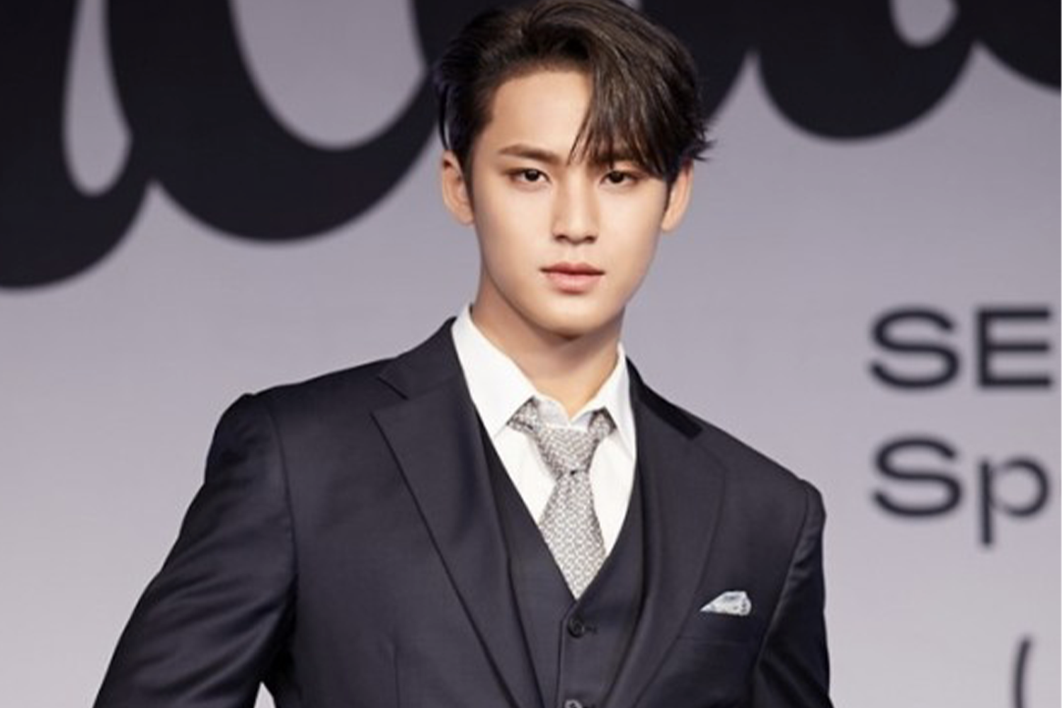 穿著正裝的人在活動現場，背景有大型橫幅，可能是在某個大型活動或新聞發布會上。