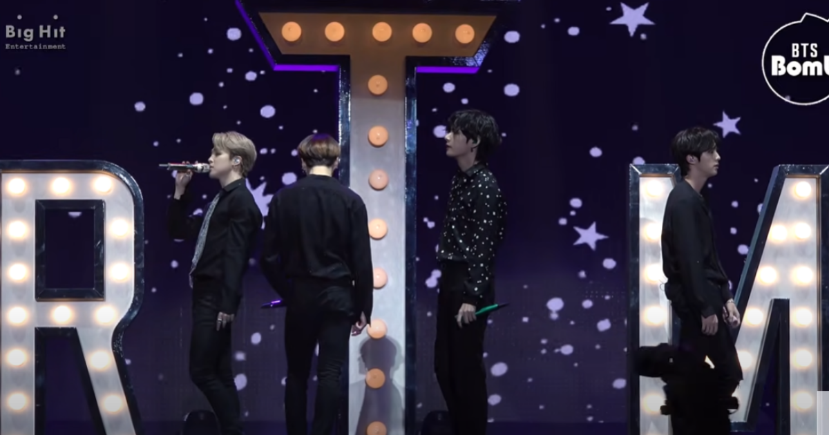 BTS、エクボのステージパフォーマンス中。背景に大きなアルファベットと星の装飾。