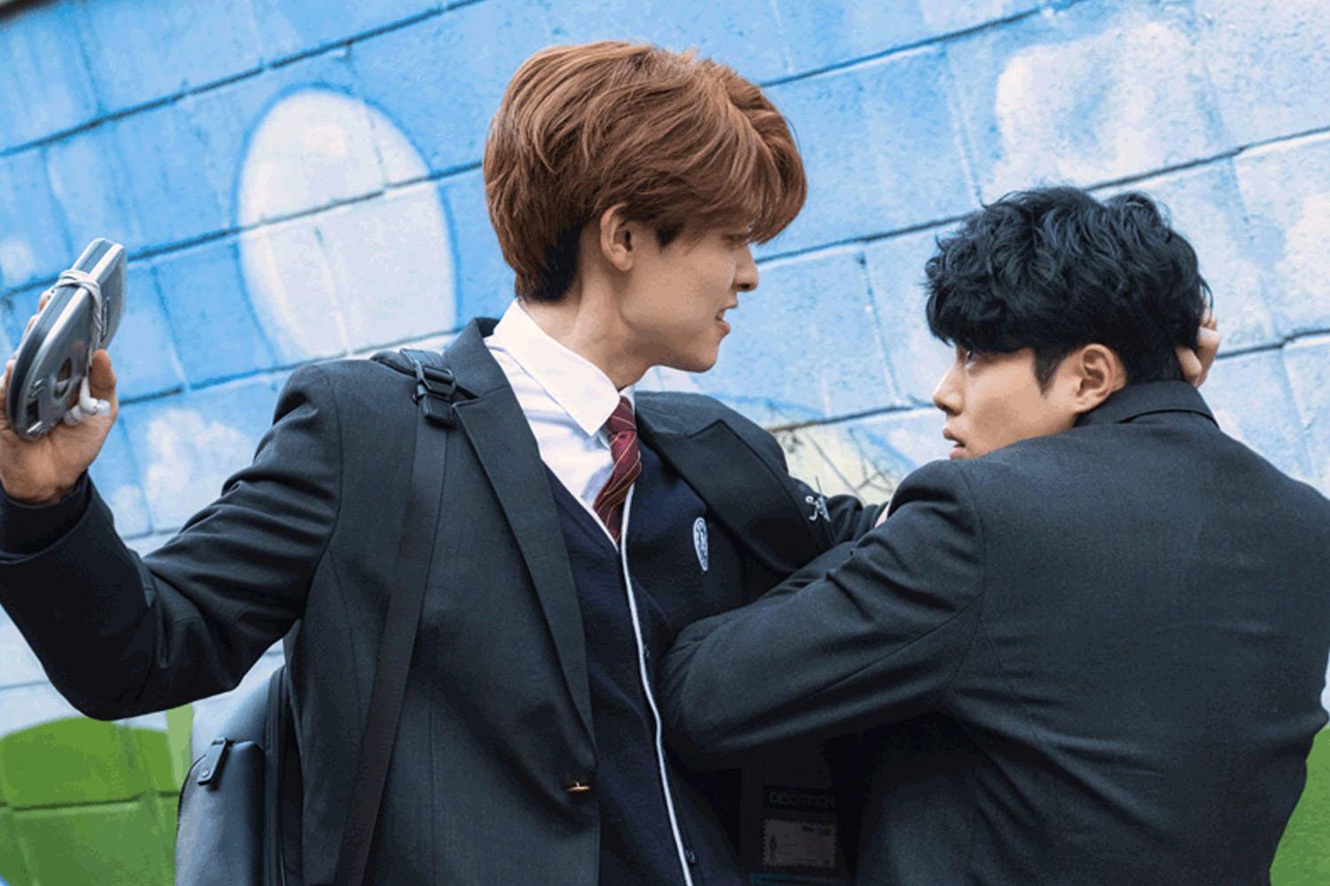 นักเรียนในห้องเรียนกำลังสวมเครื่องแบบ ดูเหมือนจะอยู่ในการสนทนาหรือกิจกรรมที่ครูให้ทำร่วมกันเน้นการศึกษาและความร่วมมือ