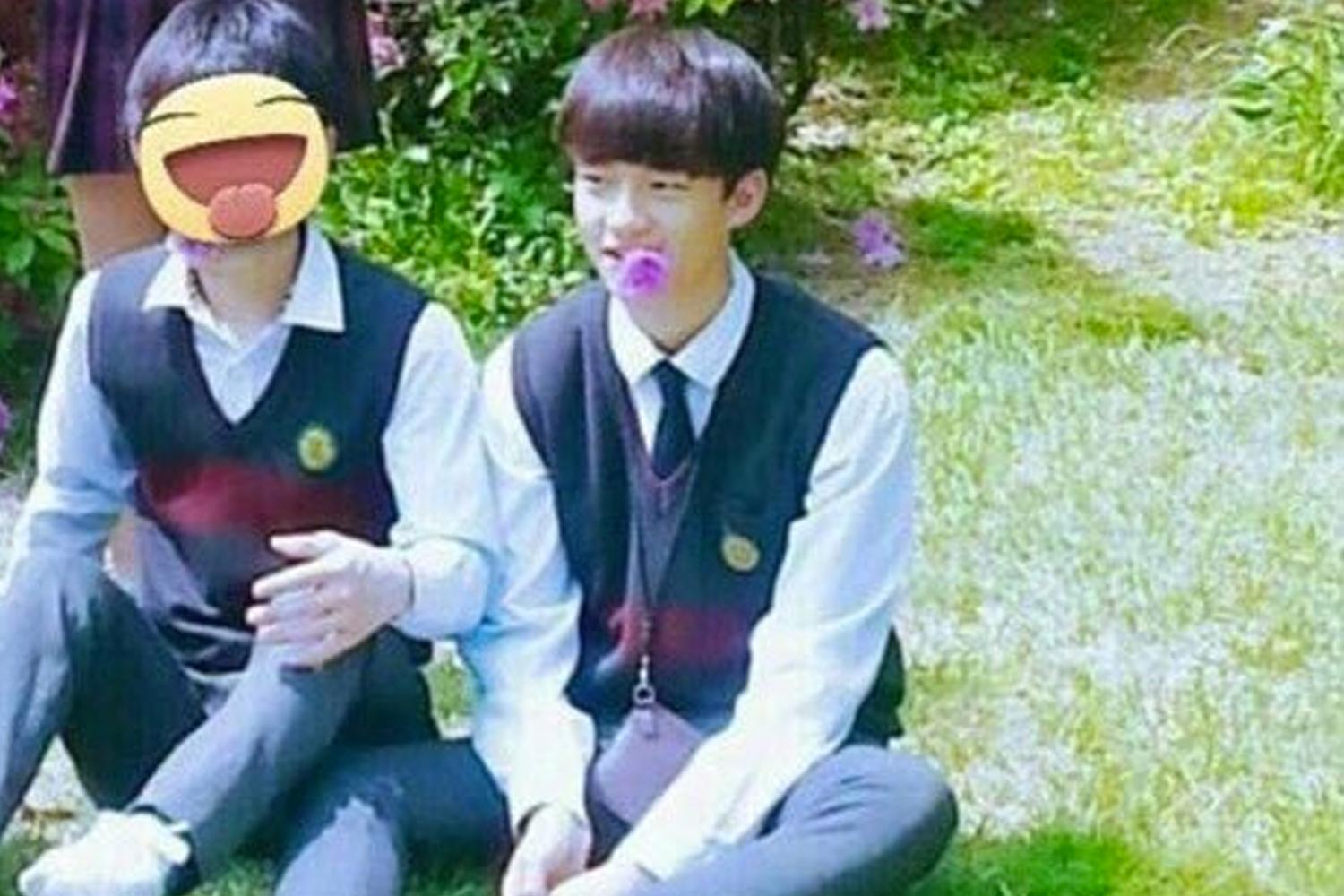 นักเรียนสองคนนั่งอยู่บนสนามหญ้า หนึ่งในนั้นคือฮยอนจินและสวมชุดยูนิฟอร์ม, ข้อกล่าวหาเรื่องความรุนแรงในโรงเรียนโดยคนรู้จักในอดีต