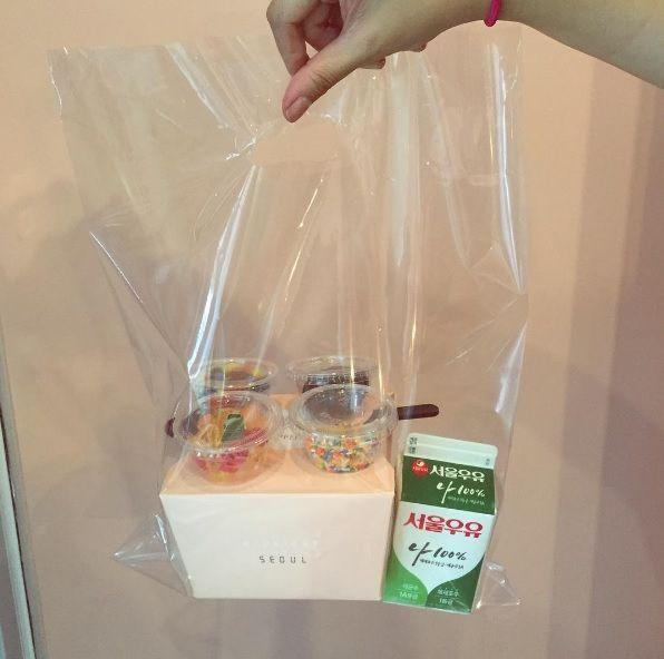 Transparent takeaway bag from Midnight in Seoul, including a branded pink box and a carton of Seoul milk.