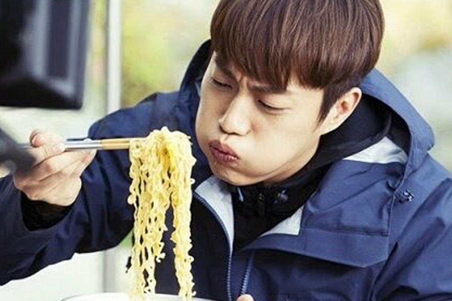 ภาพแสดงการกินราเมนด้วยตะเกียบ ซึ่งเป็นการแสดงถึงวัฒนธรรมอาหารที่เน้นเส้นและแป้งของชาวเกาหลี สะท้อนถึงเอกลักษณ์เฉพาะตัวในการรับประทานอาหาร.