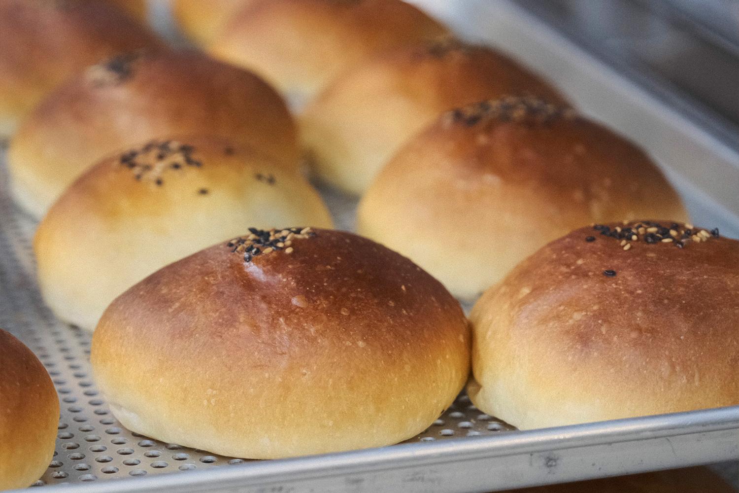 店內展示著多種包裝精美的紅豆麵包，價錢標示在框架裡，吸引潛在顧客的目光。