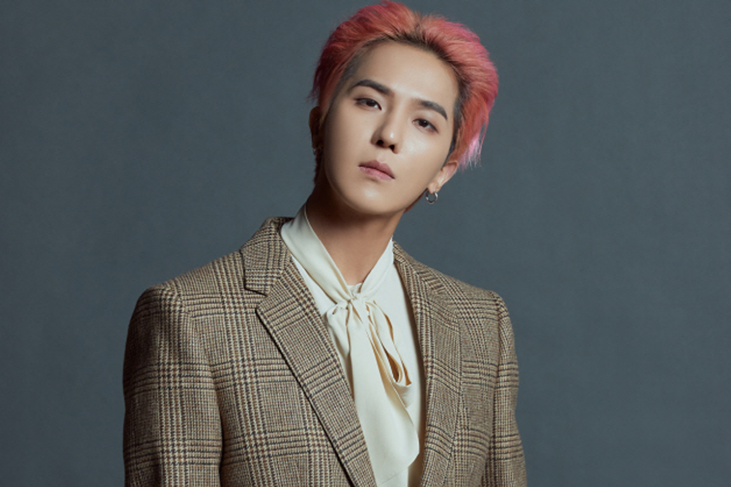 WINNER 成員 MINO 穿著格紋西裝，搭配粉紅色髮色，背景為灰色。