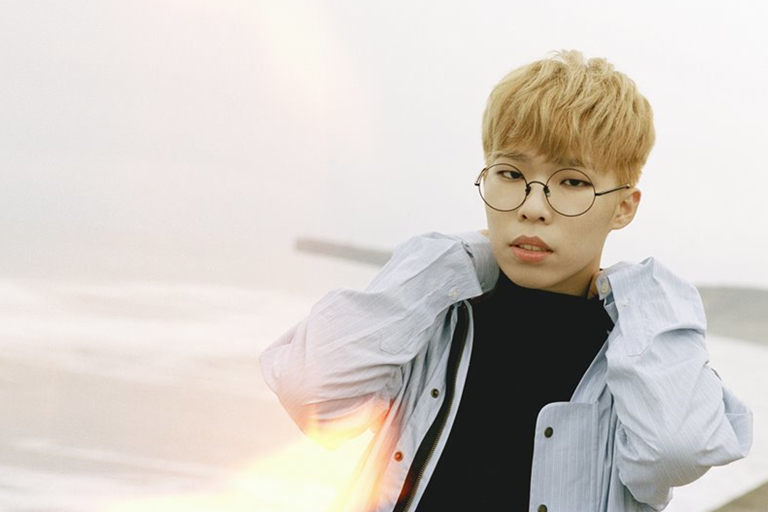 樂童音樂家燦赫穿著白色襯衫在海邊的照片，背景為灰色和白色。