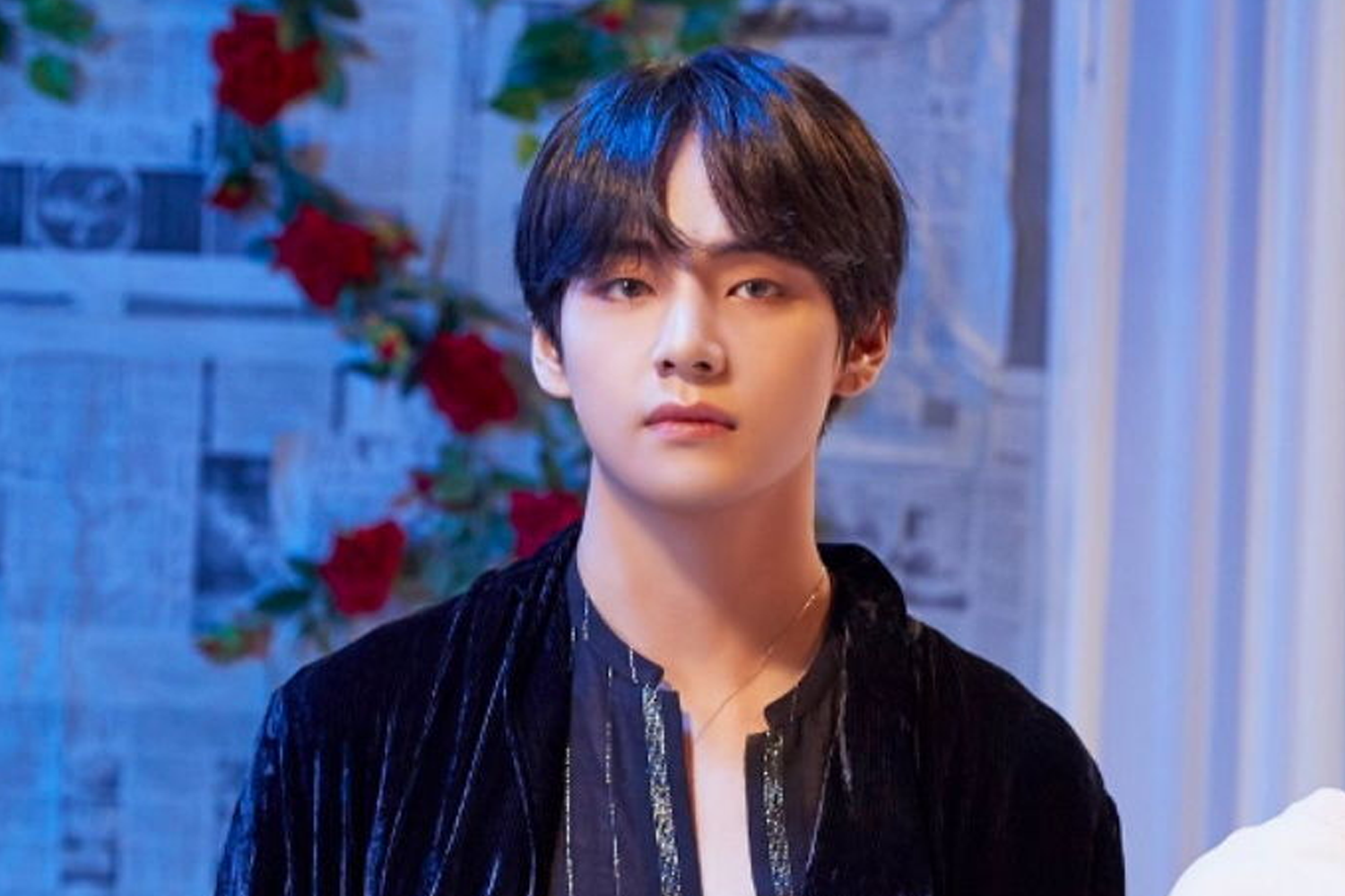BTS 成員 V 穿著黑色上衣站在玫瑰裝飾前，背景為淡紫色。