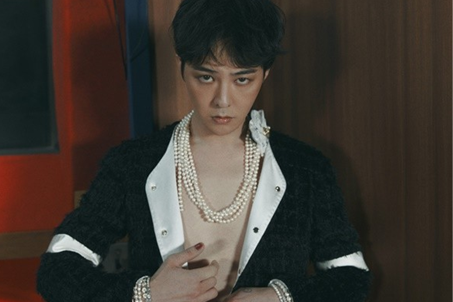 BIGBANG 成員 G-Dragon 身穿黑色毛衣，搭配多串白色珠鍊，背景為深色單色。