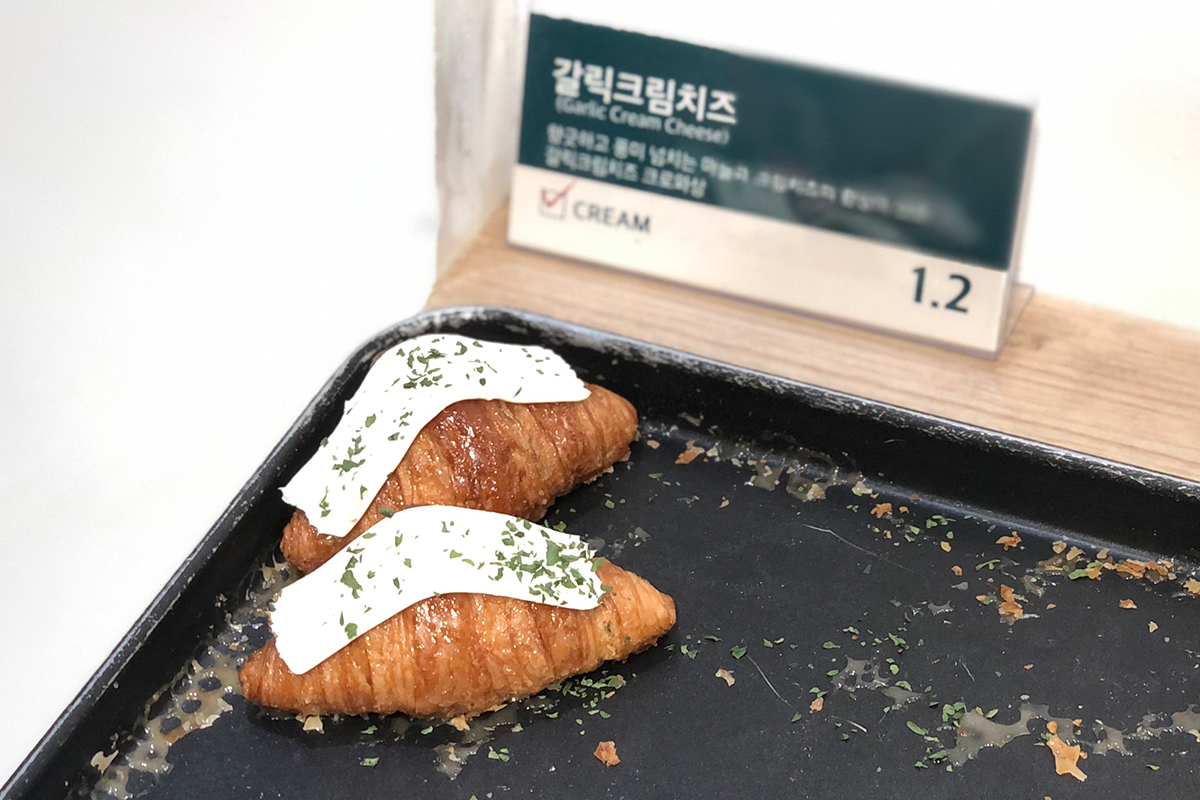 大蒜芝士牛角包，上頭灑滿香草調味料，擺放在克拉商店的櫃台上。