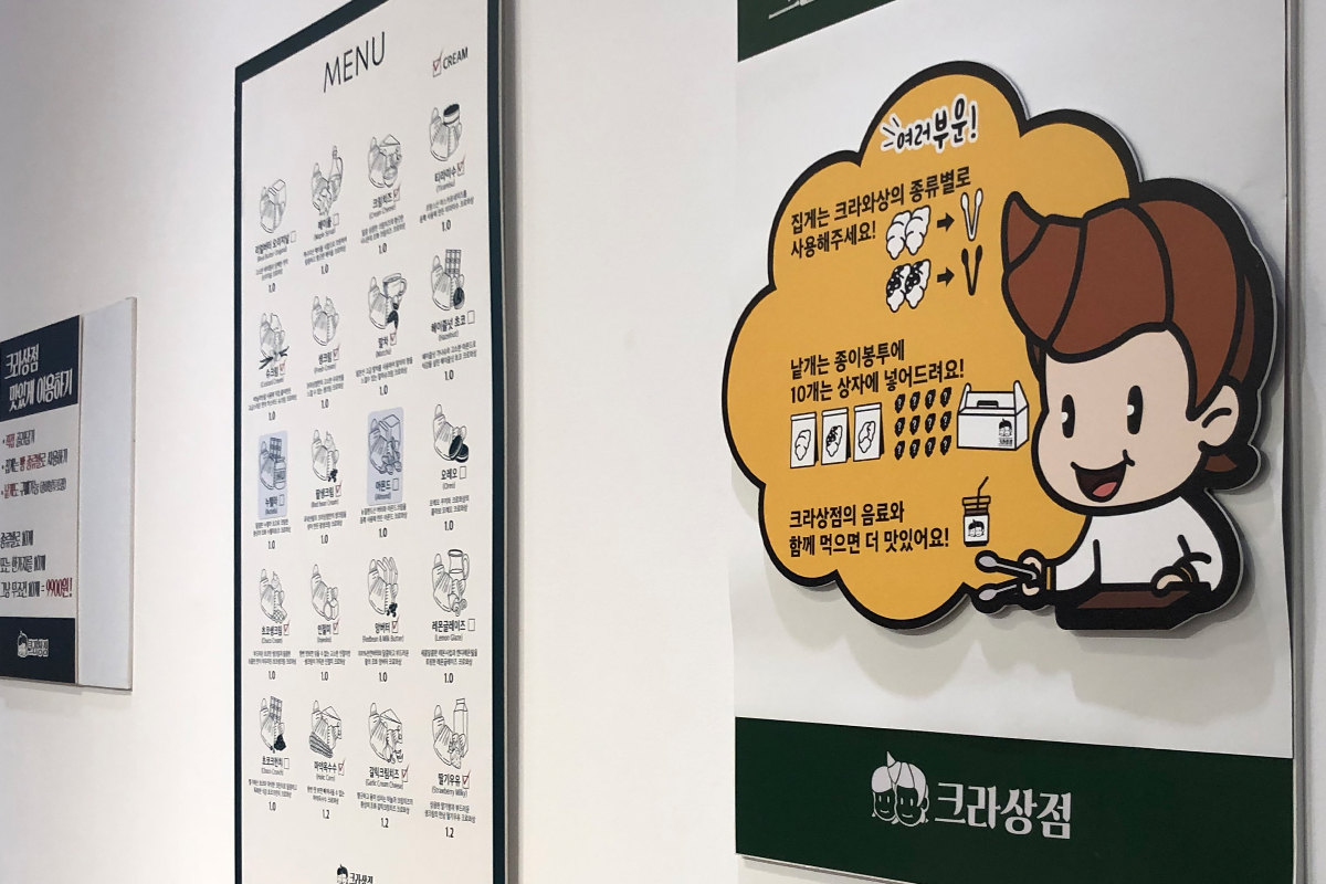 店內擺放著用墨綠色與卡通插圖裝飾的牆面，展示這家餐廳的菜單和介紹。