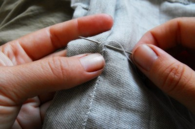 needle piercing through grey fabric while sewing