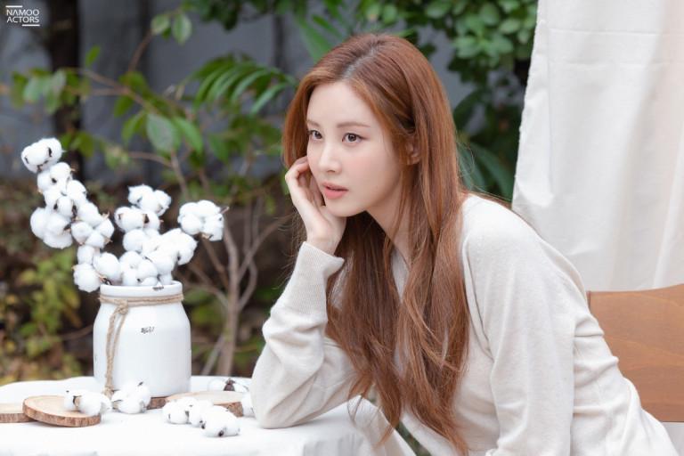 徐玄坐在白色桌子旁，手撐著臉，桌子上擺放著棉花裝飾。