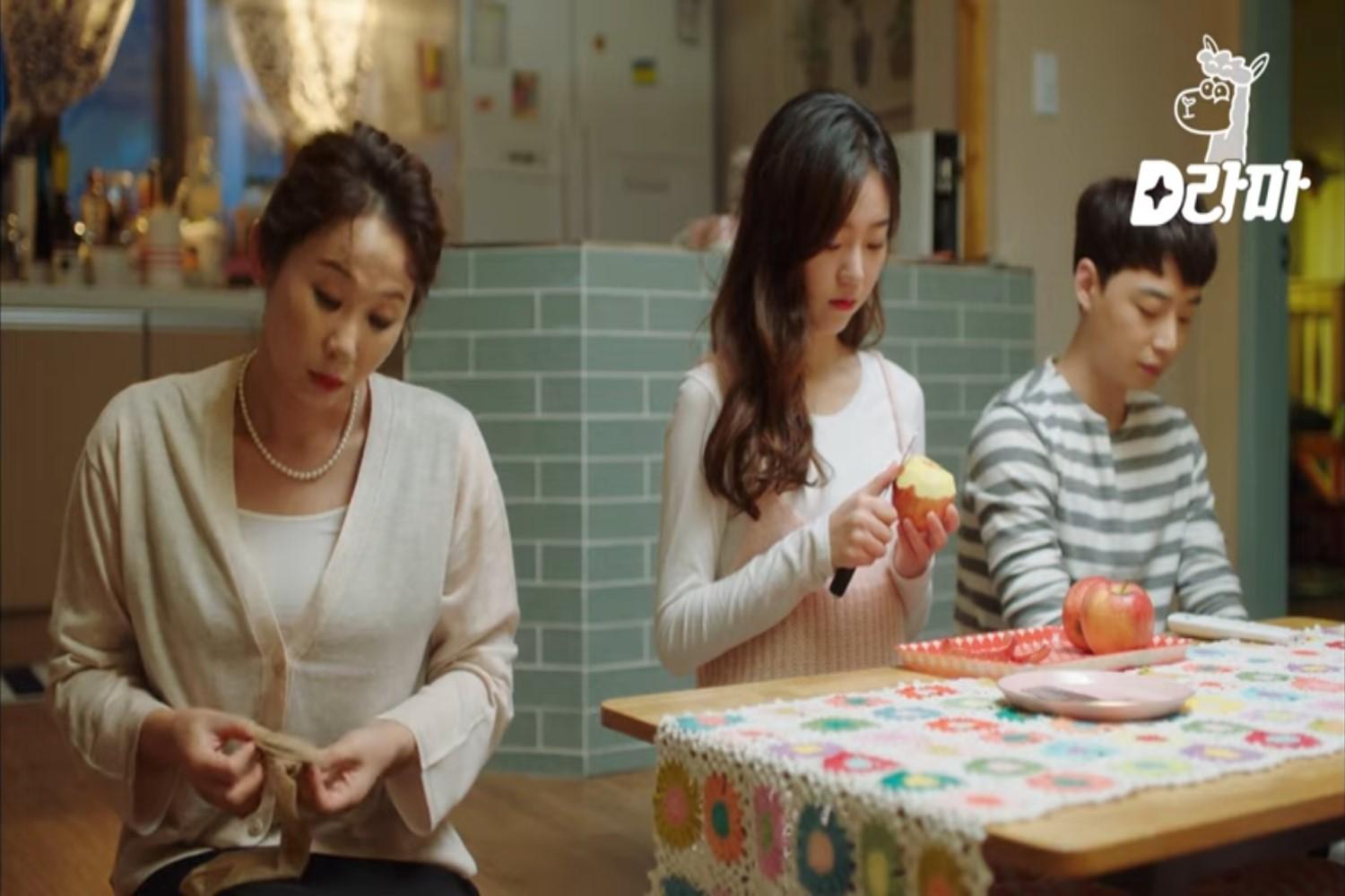 キッチンテーブルでりんごを皮むきしているシーン。果物の消費が生ゴミの増加につながる韓国文化の一例。