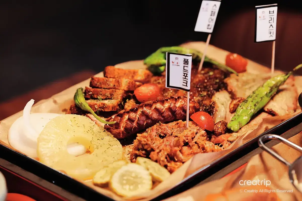 Korean BBQ platter at Ghost Black extension featuring sliced grilled meats with pineapple and assorted vegetables, capturing the essence of American-style barbecue in a South Korean setting.