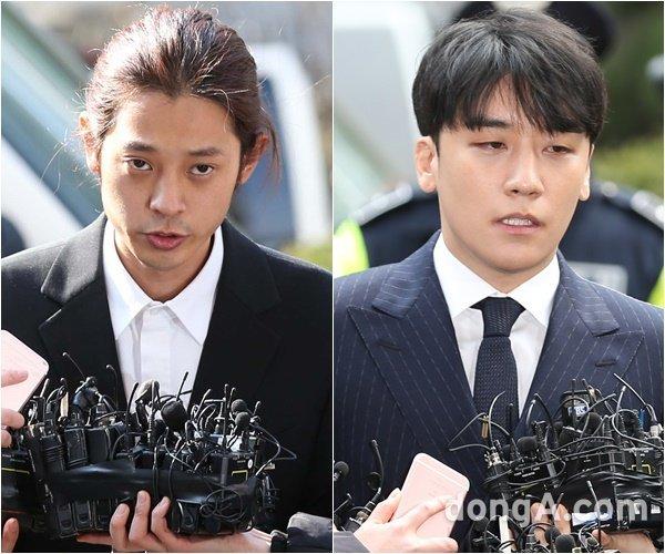 スーツ姿の男性と共に取材陣のインタビューを受ける人物。