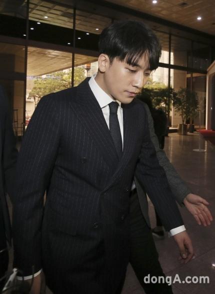 裁判所の入口で取材陣から注目される、スーツを着た男性。