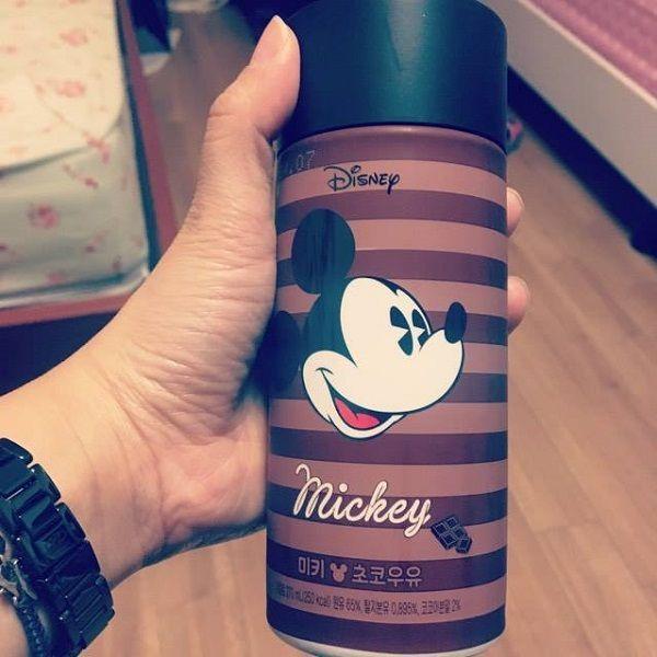 A hand holding a Seoul Milk Mickey Mouse chocolate milk bottle designed with striped patterns, highlighting new themed milk products available for a limited-time offer.