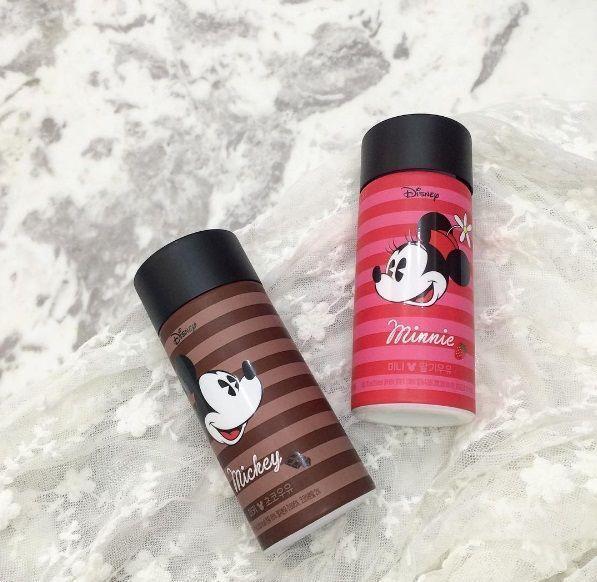 Two Seoul Milk bottles displaying Mickey and Minnie Mouse with distinctive striped designs set against a lace backdrop, featuring a chocolate milk flavor for Mickey and strawberry milk for Minnie.