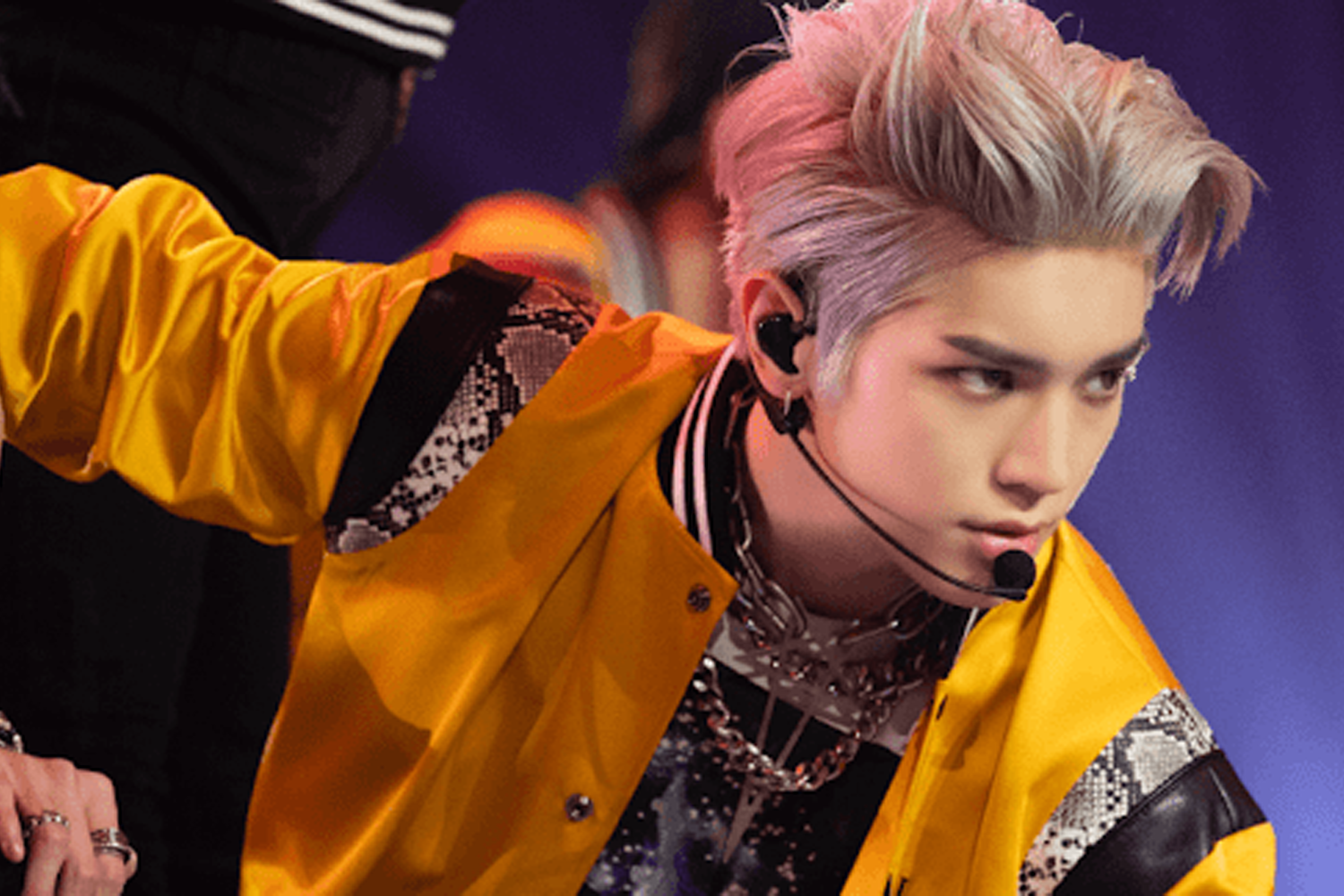 NCT成員泰容正在舞台上，穿著亮眼的黃色外套，展現出充滿活力與時尚的偶像形象。