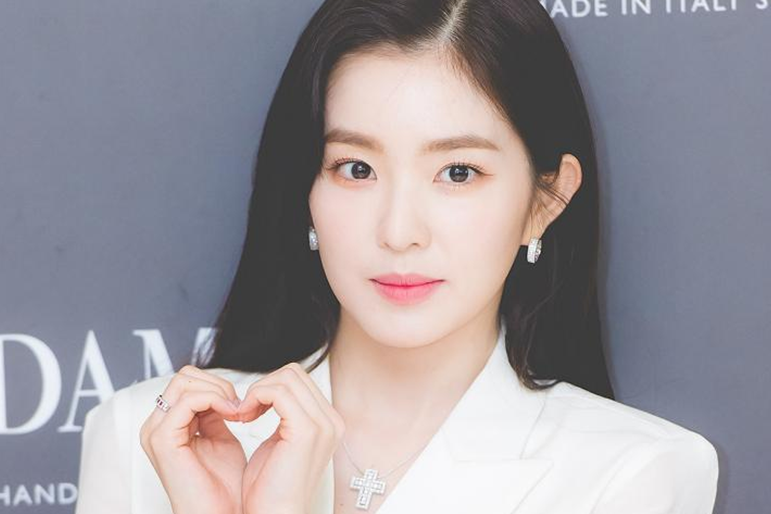 紅貝貝成員Irene身穿白色西裝，手握愛心姿勢，背景是深灰色的牆面，凸顯她的高雅與時尚感。