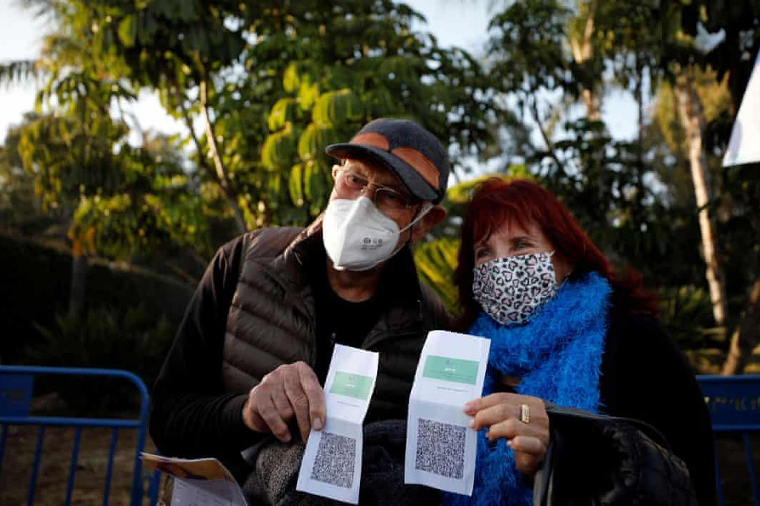 一對人展示綠色通行證，背景是樹木和户外環境。