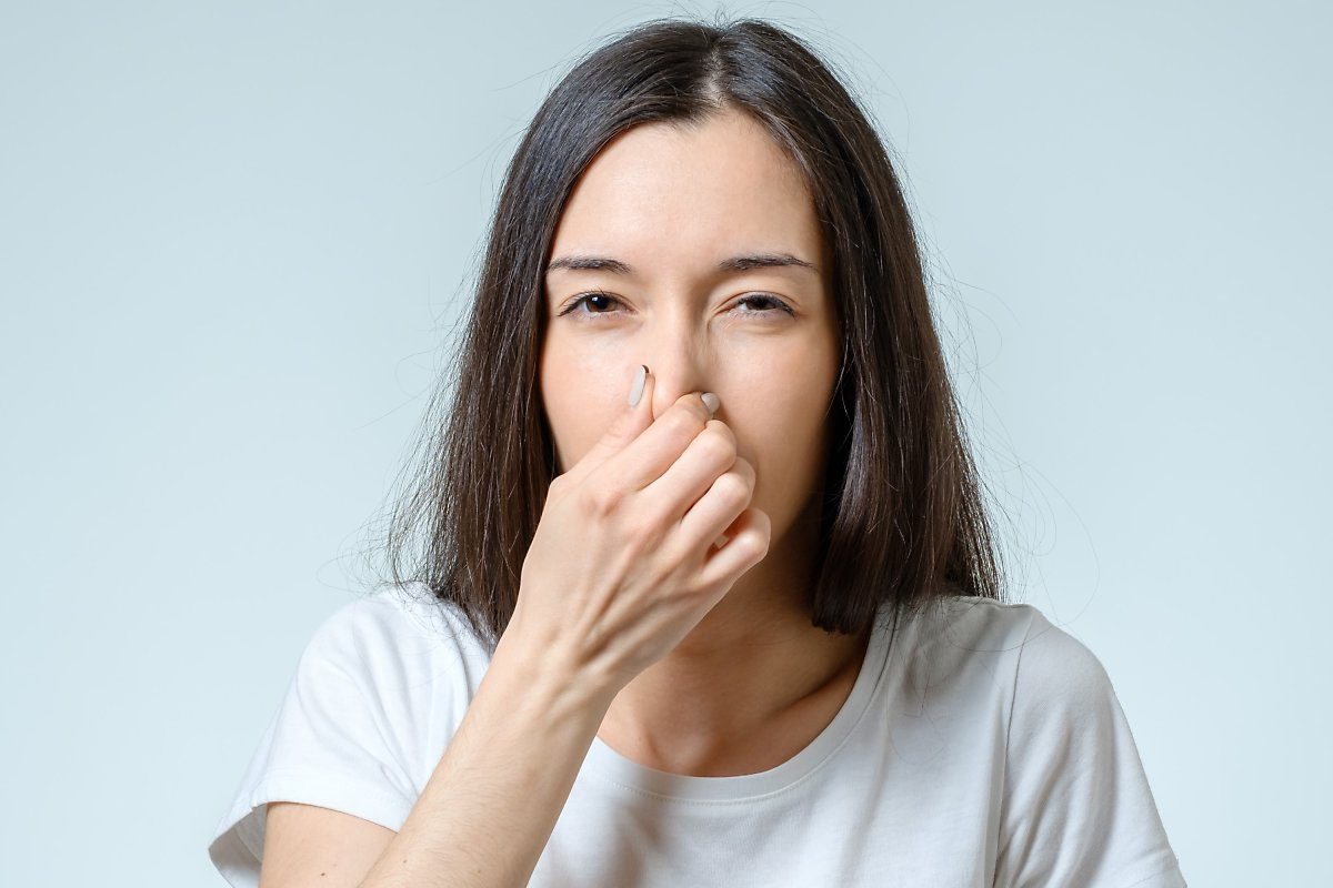 女性因异味问题捂住鼻子,讨论韩国人无体臭基因的现象。