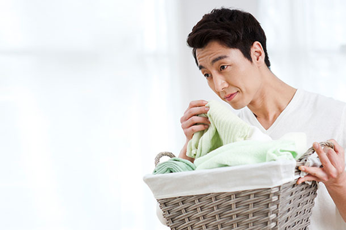 一名年轻人闻干净衣物,强调韩国人使用衣物芳香剂保持清新的习惯。