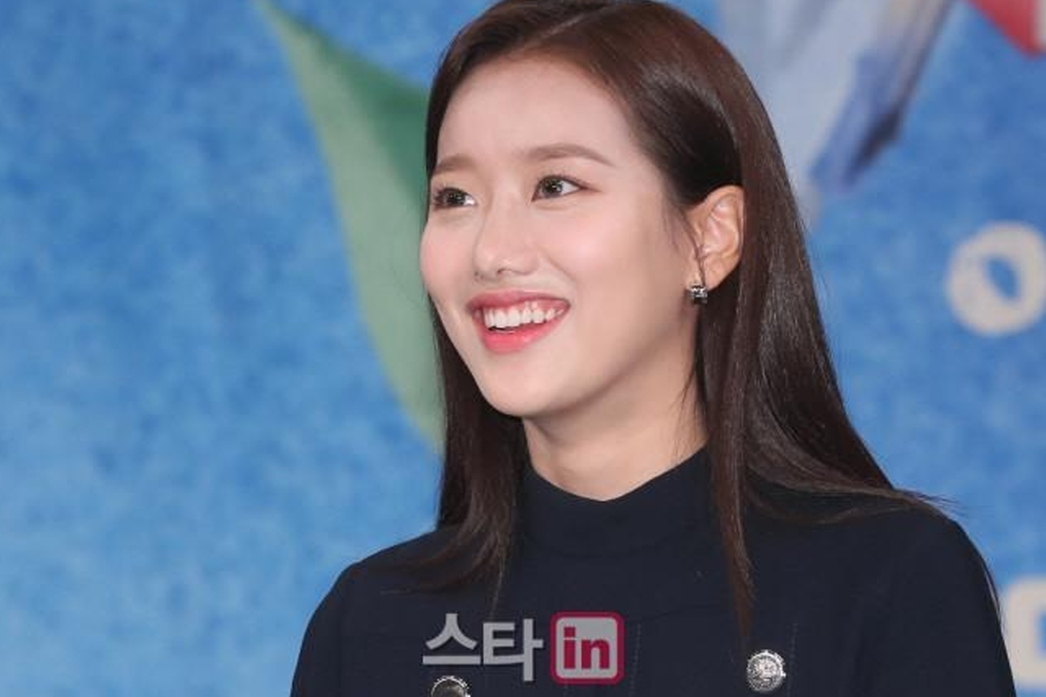 穿黑色服裝的模特在藍色背景前參加活動，背景顯示'Sta in'字樣的標誌。