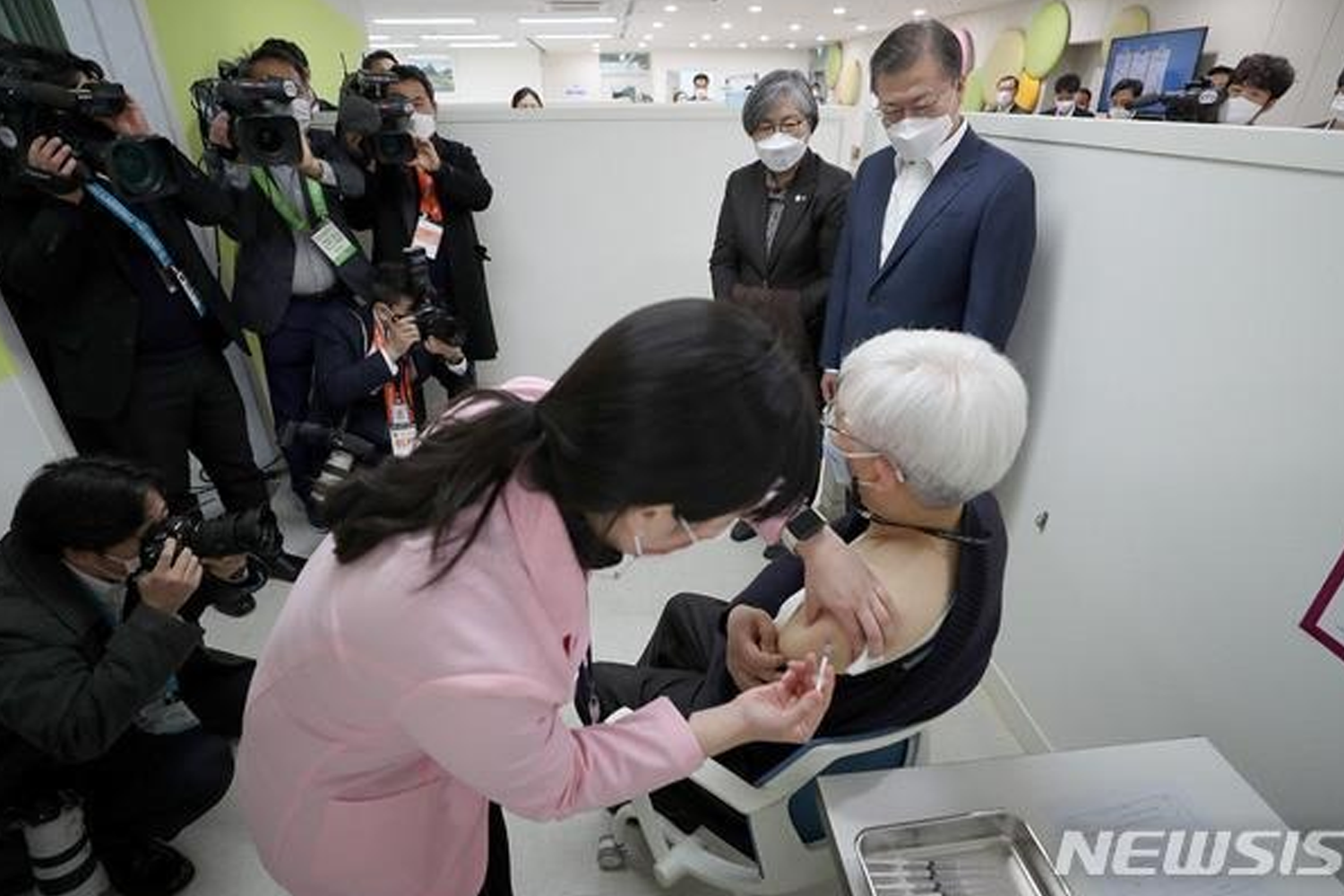 醫護人員為年長者注射疫苗，現場有多位媒體記者在拍攝。NEWSIS 提供的新聞畫面。