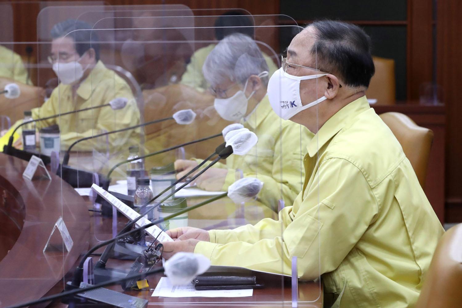 การประชุมเพื่อหารือเกี่ยวกับข้อตกลงระหว่างประเทศในการดำเนินโครงการ Travel Bubble ในเกาหลีใต้ ตัวแทนสวมหน้ากากและเสื้อสีเหลืองนั่งประชุมหลังแผงกัน COVID-19