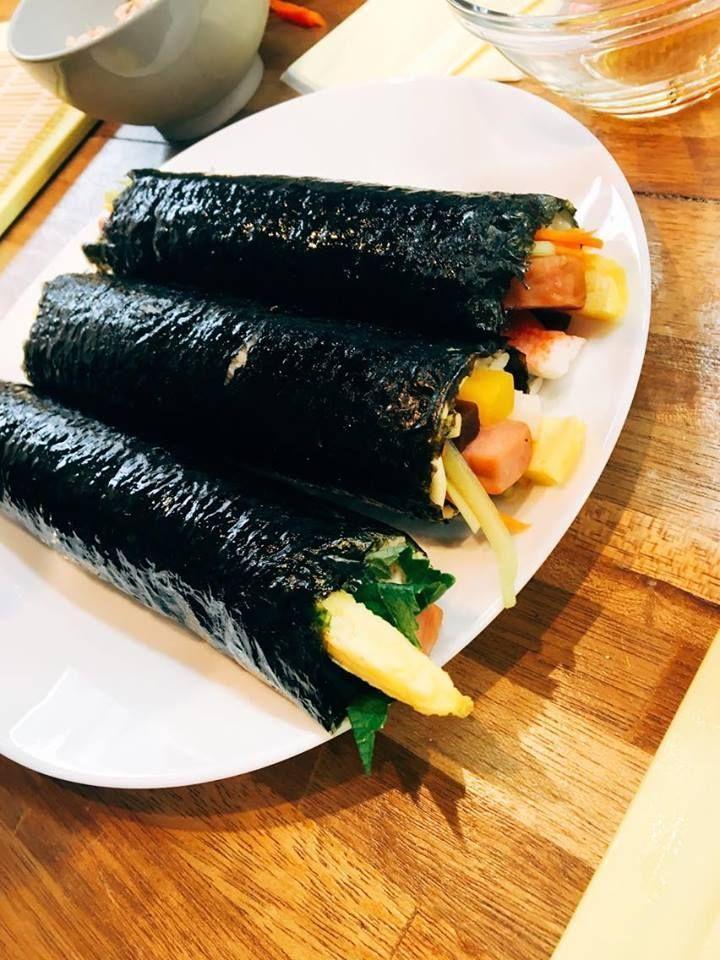 Three Korean kimbap rolls placed on a white plate on a wooden table.