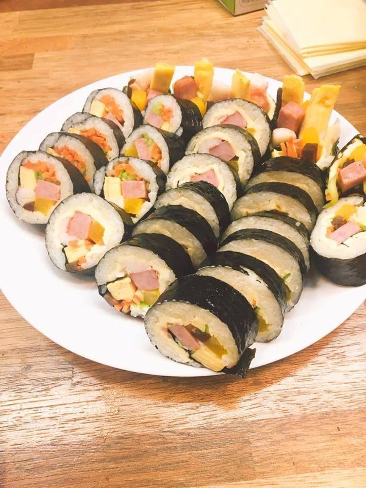 Plate of assorted Korean kimbap rolls with colorful ingredients including ham and pickled radish.