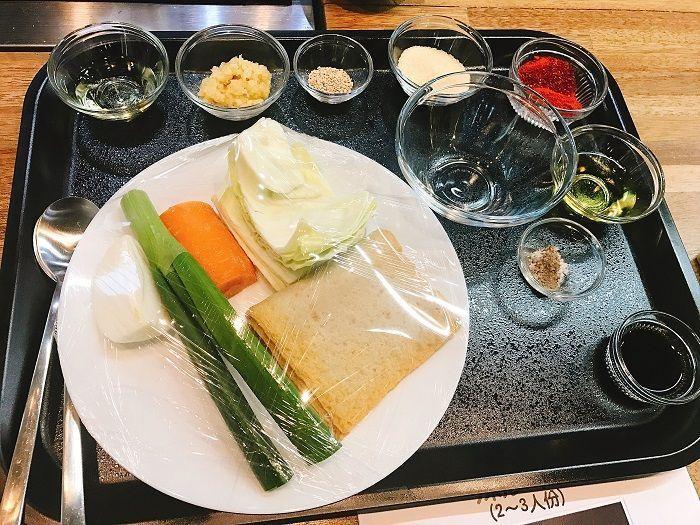 Tray with ingredients for tteokbokki including onion, green onion, dried fish cake, and seasonings, neatly arranged.
