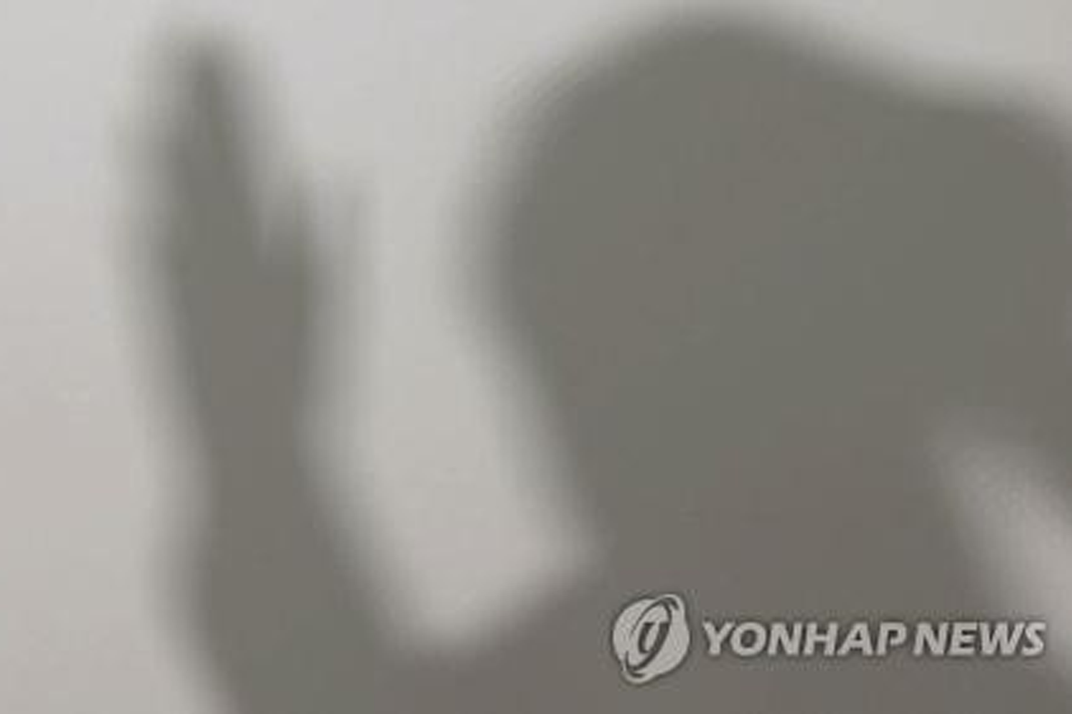 一位戴着帽和口罩的男子和一位女子正在被記者圍住，他們穿着白色衣服，兩人低下頭面對媒體氛圍。