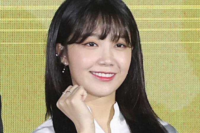 韓国のアイドルApinkのウンジ、白い衣装を着ており、インタビューに答えている様子が見られます。画面に向けて手をかざしている姿です。