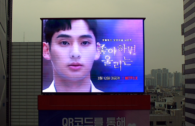 ข้อความแสดงบนจอขนาดใหญ่โปรโมทซีรีส์ Love Alarm โดยมีชื่อซีรีส์ปรากฏบนภาพ.