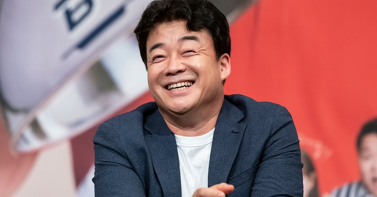 韓國名廚白種元的訪談會上，身著西裝的白種元坐在桌邊，背景中有訪談會的標誌。