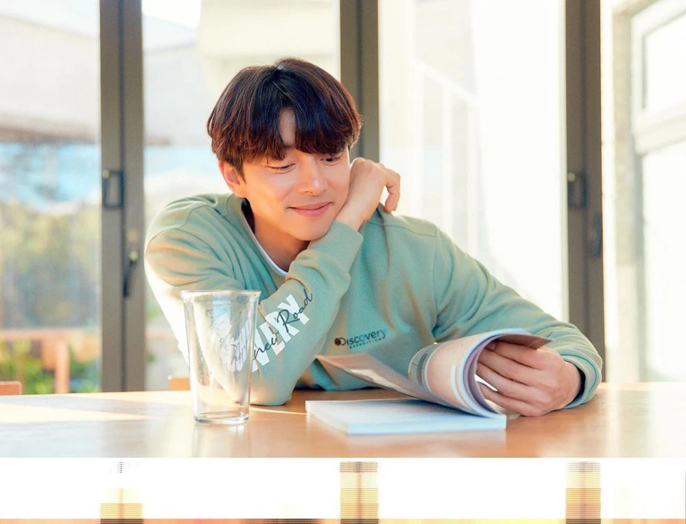 手托下巴坐于桌旁的孔刘，身着薄荷绿色卫衣，诠释Discovery 2020年春季系列的家居休闲概念。