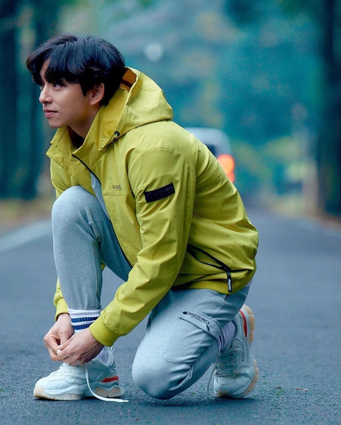 孔刘身穿暗绿色Discovery夹克，凝视窗外，营造出探索者的魅力和时尚风度。