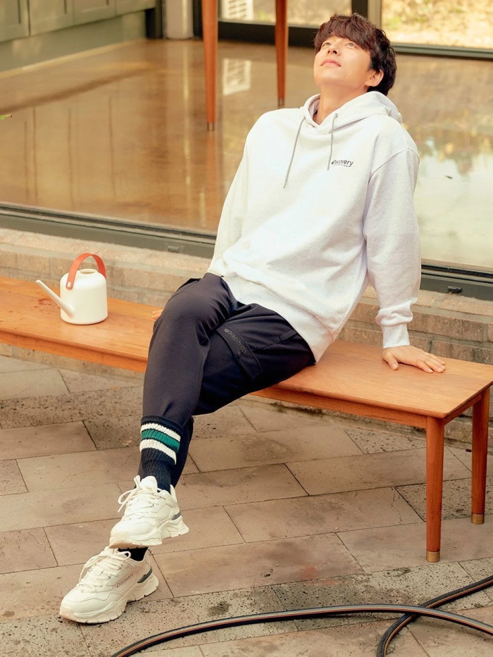 孔刘穿着宽松的Discovery家居服，站在室外长椅上伸展着身体，展示自由及生活方式的魅力。