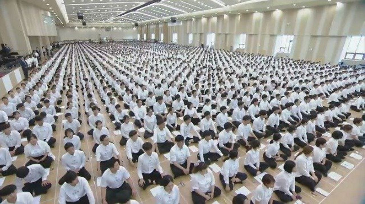 新天地教會室內大型聚會，場內信徒身穿白色襯衣整齊排列。