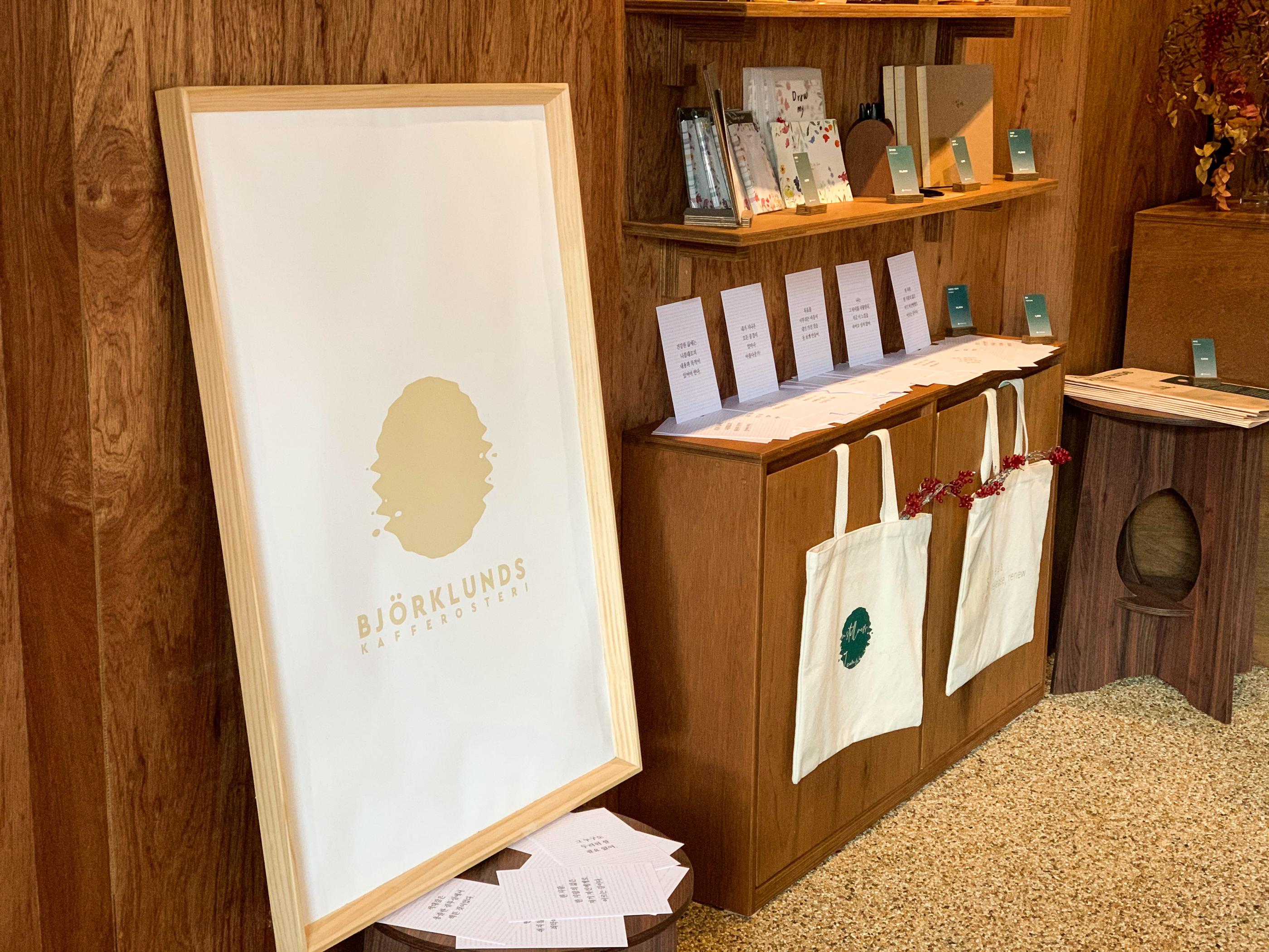 Bảng logo quán bjorklunds cùng các túi vải trưng bày, thể hiện phong cách cổ điển và lịch lãm tại không gian quán sang trọng.