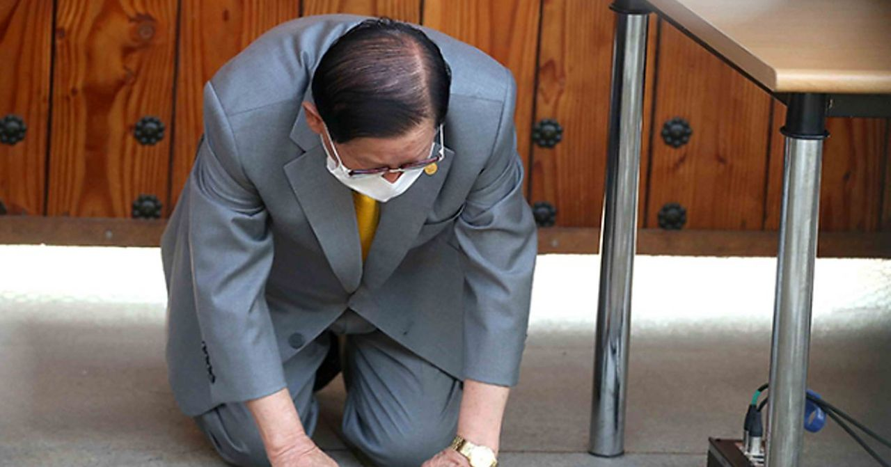 一名男性穿著西裝跪下，表示懇求或表示歉意。