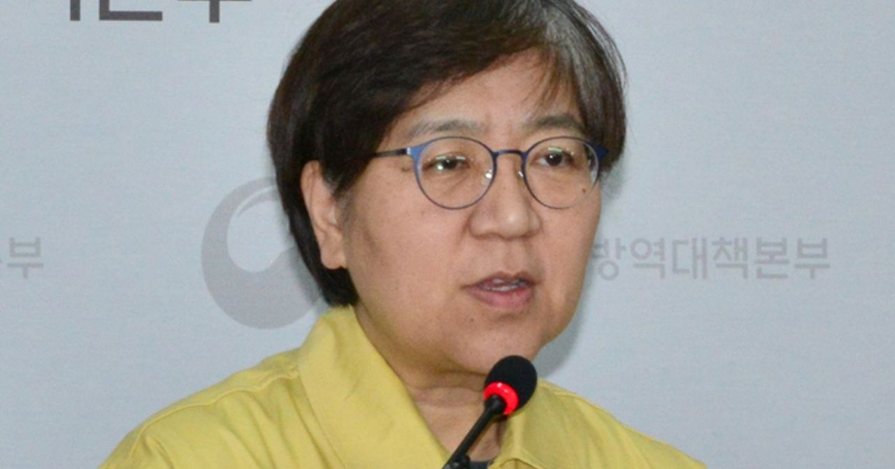 防疫官員穿著黃色外套，站在麥克風前發言，背景有韓文標識，圖片來源為韓國傳染病預防和控制中心。